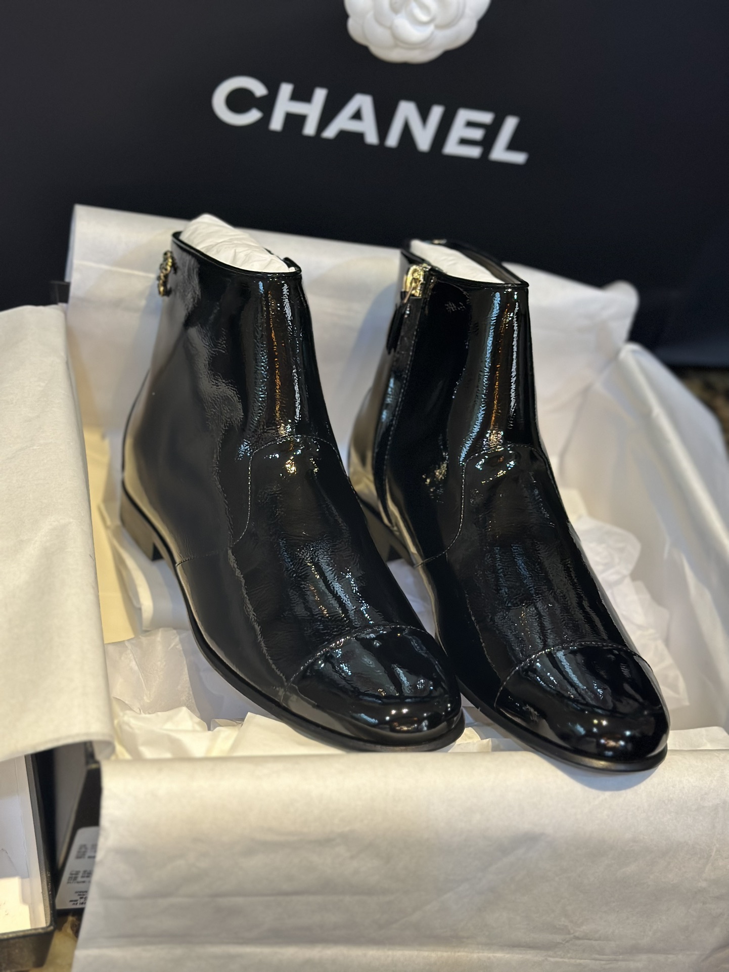 Chanel 23a Crinkled Patent Leather Chelsea Boots: A pair of understated yet exquisitely crafted ankle boots. Featuring sleek black patent leather with subtle gloss, minimalist design with only a brand logo decoration on the vamp. The interior is lined wit