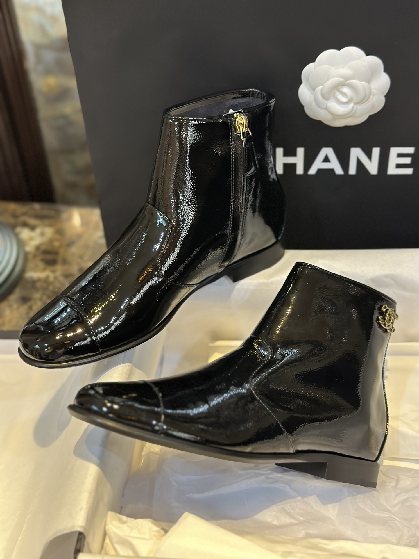 Chanel 23a Crinkled Patent Leather Chelsea Boots: A pair of understated yet exquisitely crafted ankle boots. Featuring sleek black patent leather with subtle gloss, minimalist design with only a brand logo decoration on the vamp. The interior is lined wit