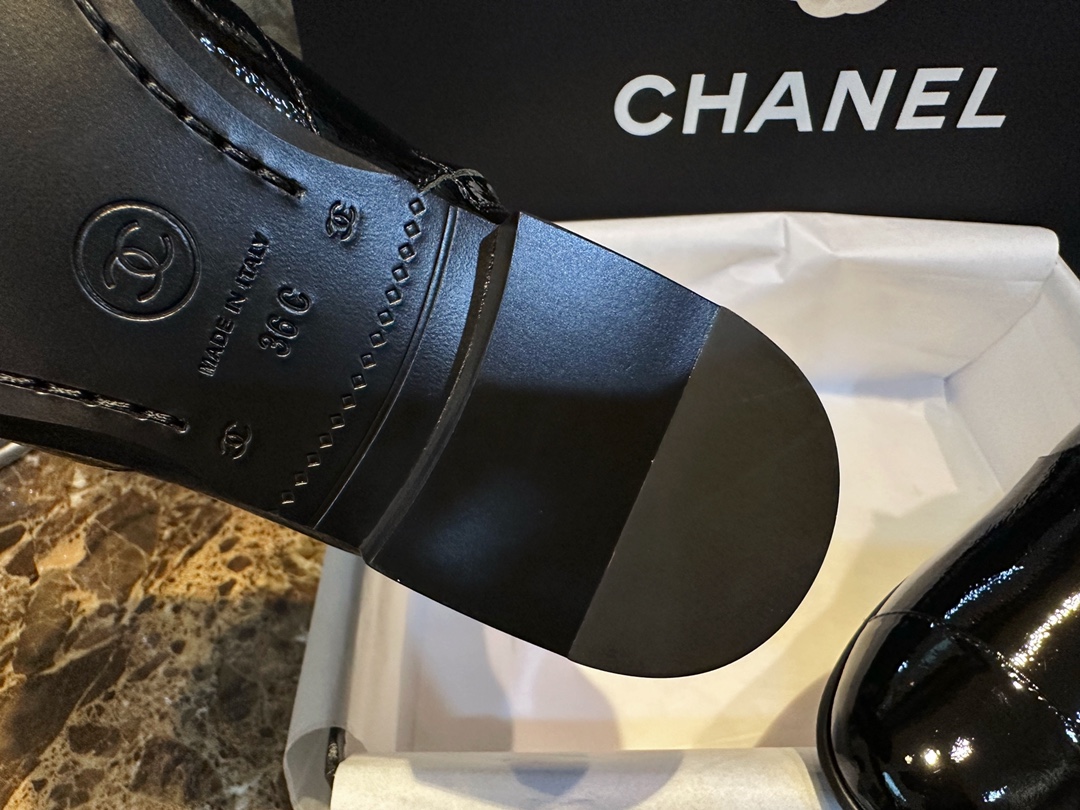 Chanel 23a Crinkled Patent Leather Chelsea Boots: A pair of understated yet exquisitely crafted ankle boots. Featuring sleek black patent leather with subtle gloss, minimalist design with only a brand logo decoration on the vamp. The interior is lined wit