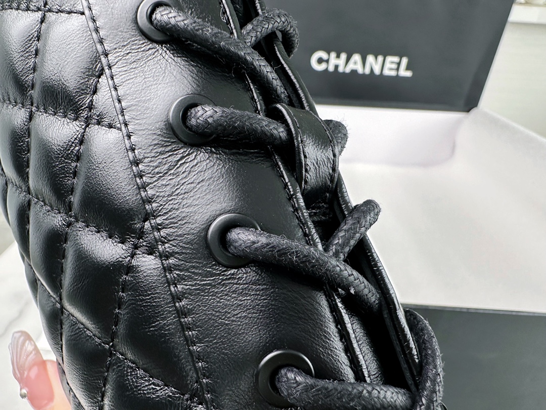 Chanel  23b  Chain Long Martin Boots: Crafted from black oil leather and black patent leather, with a leather combination sole. Classic diamond-pattern stitching and chain elements intertwine on the vamp