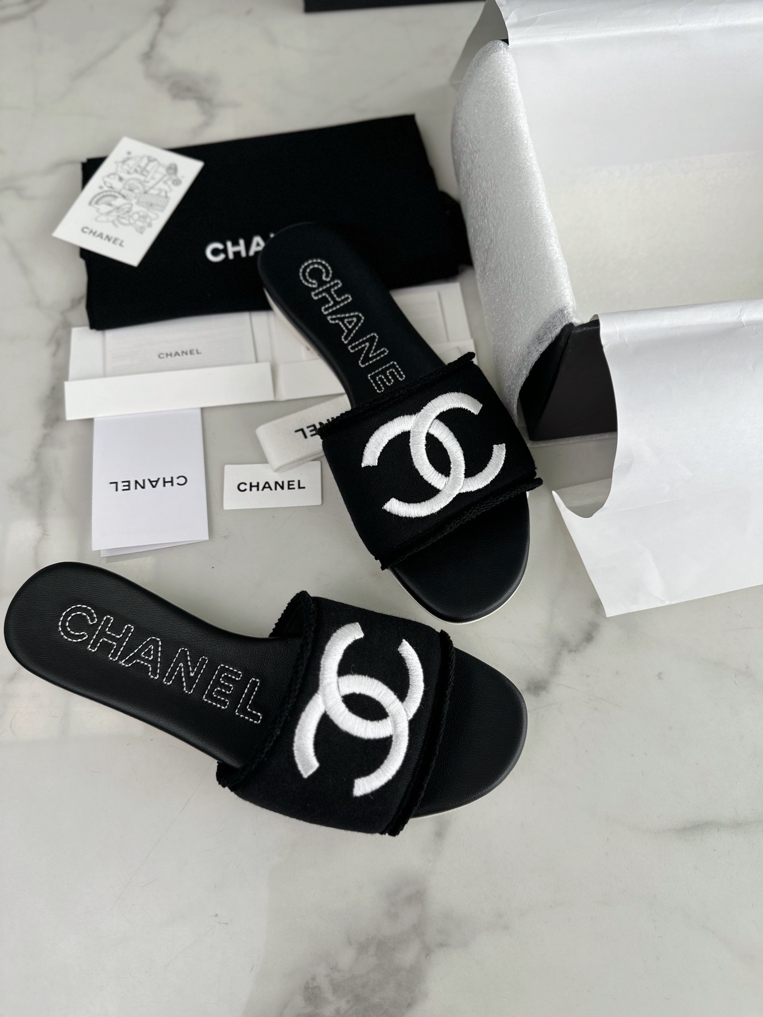 Chanel Black Double C Embroidered Slides: Featuring a Striking Black and White Color Block Design on the Upper, Karen Satin Fabric with Imported Thread Embroidery, Finished with a White Leather Sole. 