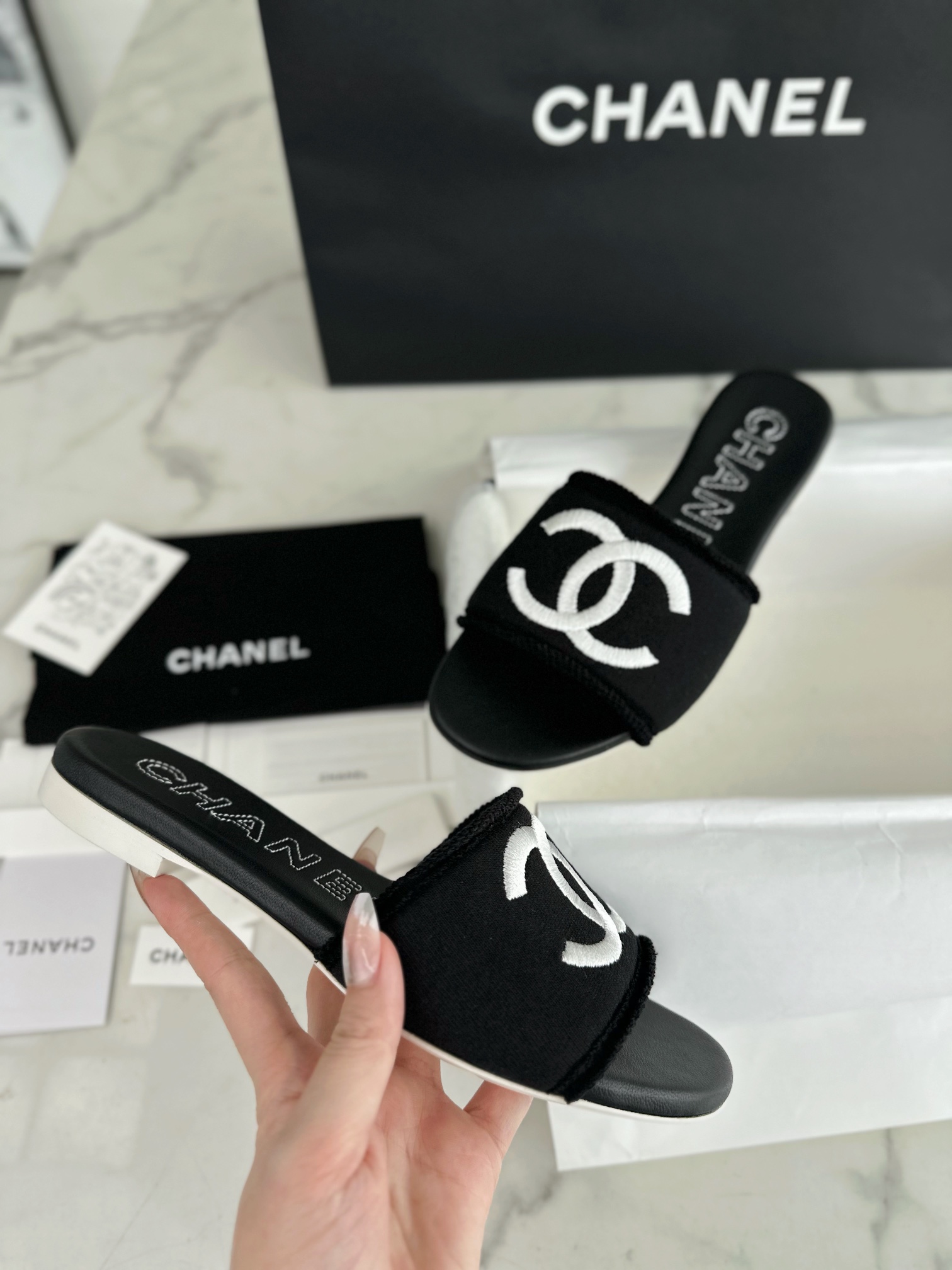 Chanel Black Double C Embroidered Slides: Featuring a Striking Black and White Color Block Design on the Upper, Karen Satin Fabric with Imported Thread Embroidery, Finished with a White Leather Sole. 