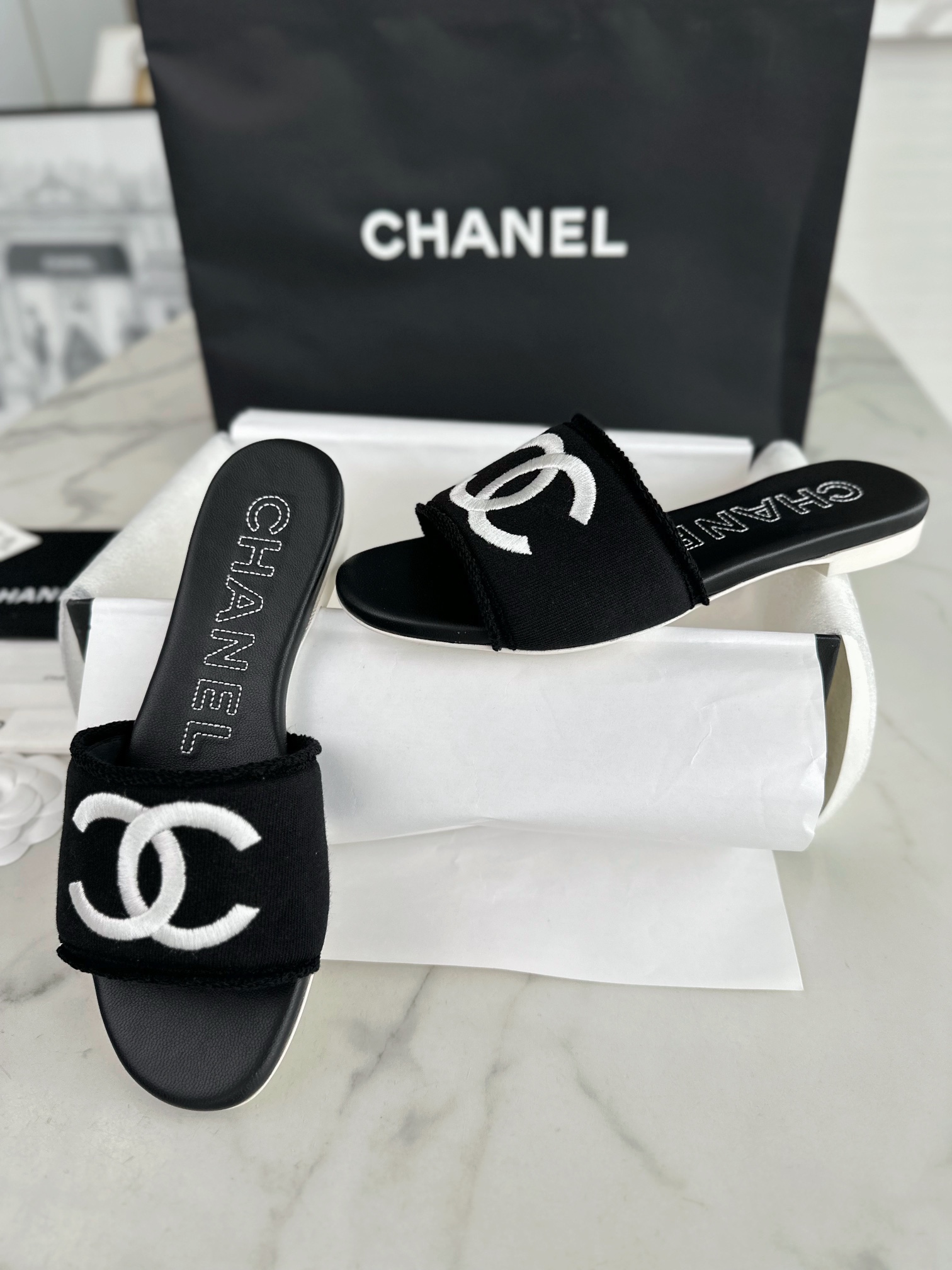 Chanel Black Double C Embroidered Slides: Featuring a Striking Black and White Color Block Design on the Upper, Karen Satin Fabric with Imported Thread Embroidery, Finished with a White Leather Sole. 