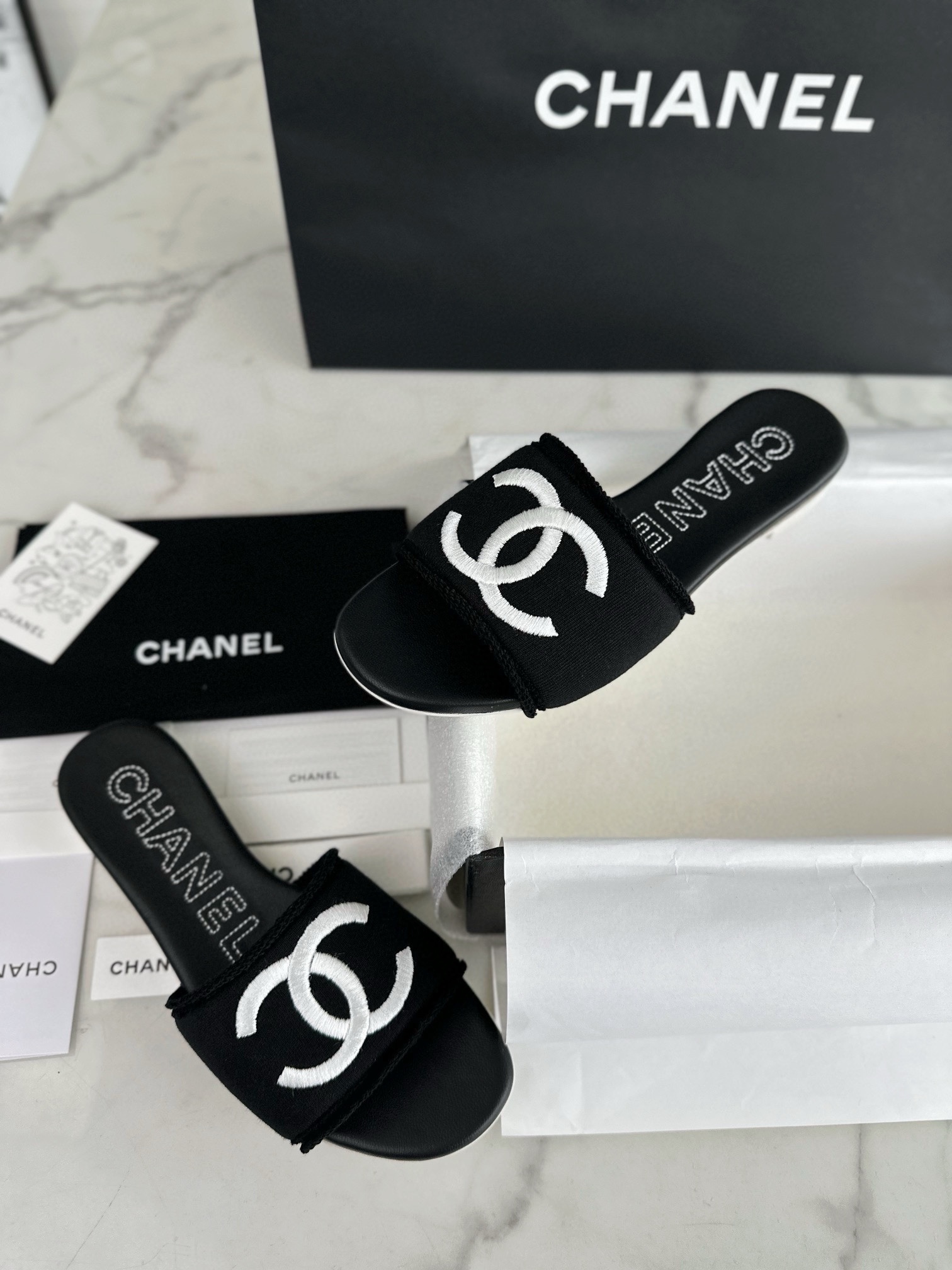 Chanel Black Double C Embroidered Slides: Featuring a Striking Black and White Color Block Design on the Upper, Karen Satin Fabric with Imported Thread Embroidery, Finished with a White Leather Sole. 