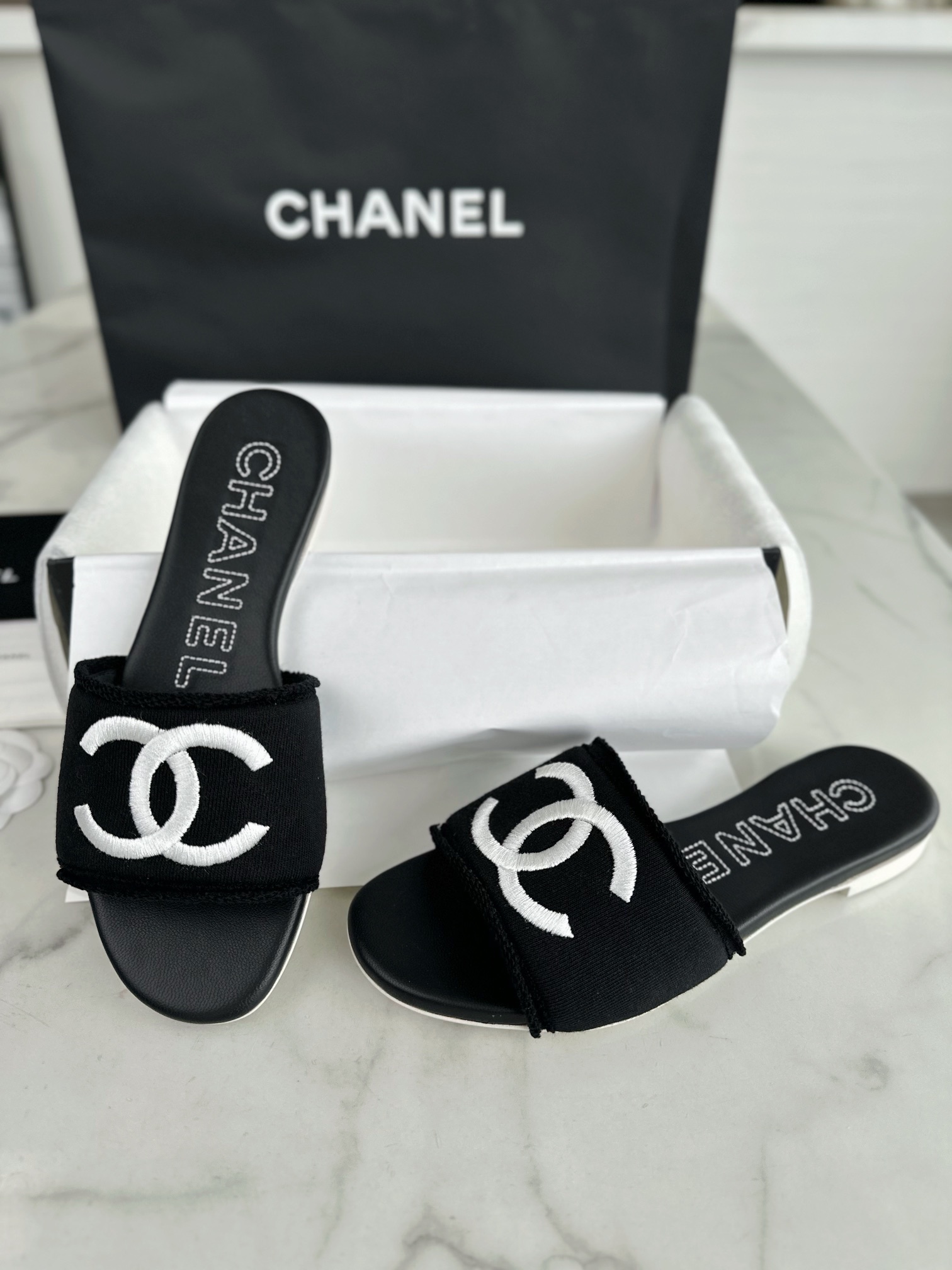 Chanel Black Double C Embroidered Slides: Featuring a Striking Black and White Color Block Design on the Upper, Karen Satin Fabric with Imported Thread Embroidery, Finished with a White Leather Sole. 